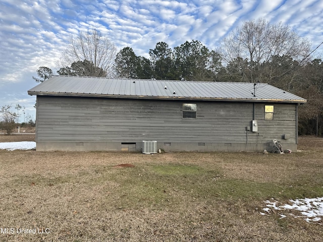 rear view of property with central AC unit and a lawn