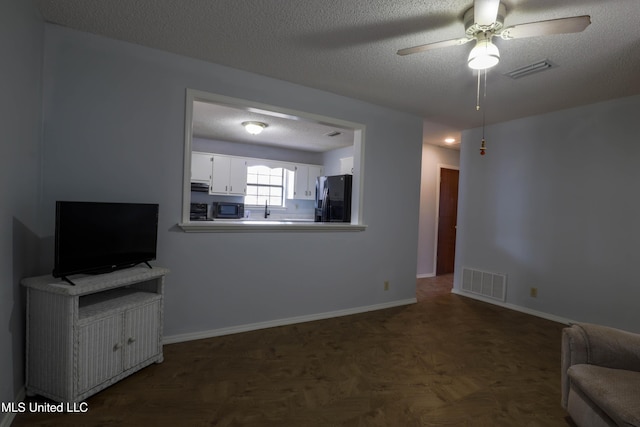 unfurnished living room with parquet floors, ceiling fan, and a textured ceiling