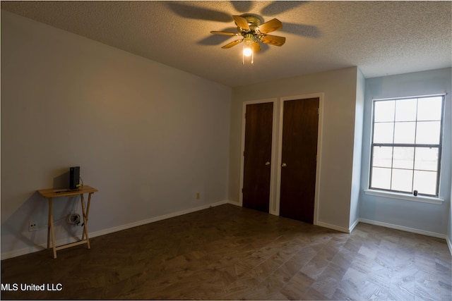 unfurnished bedroom featuring ceiling fan, two closets, and a textured ceiling