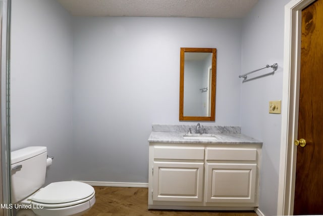 bathroom with hardwood / wood-style flooring, vanity, toilet, and a textured ceiling