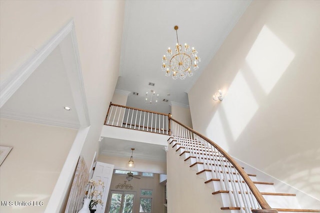 stairs featuring crown molding, a chandelier, and a high ceiling