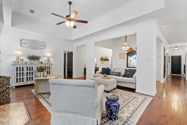 living room with a raised ceiling, ceiling fan, ornamental molding, and dark hardwood / wood-style flooring