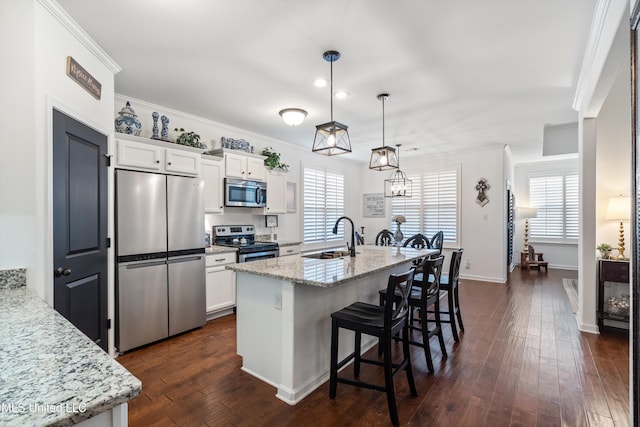 kitchen featuring light stone counters, sink, stainless steel appliances, and white cabinets