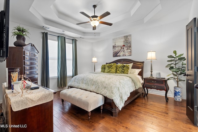 bedroom featuring hardwood / wood-style flooring, ceiling fan, and a raised ceiling