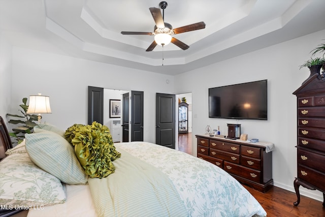 bedroom with ceiling fan, dark hardwood / wood-style floors, and a raised ceiling