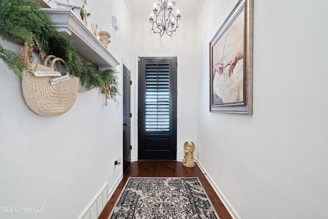 doorway featuring ornamental molding, dark hardwood / wood-style floors, and a chandelier