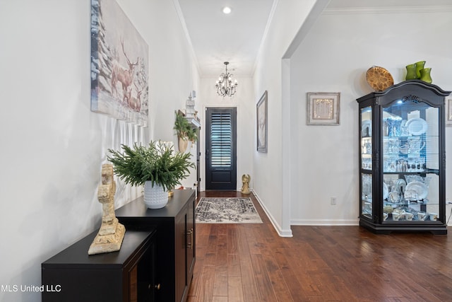 entryway featuring ornamental molding, dark wood-type flooring, and a chandelier