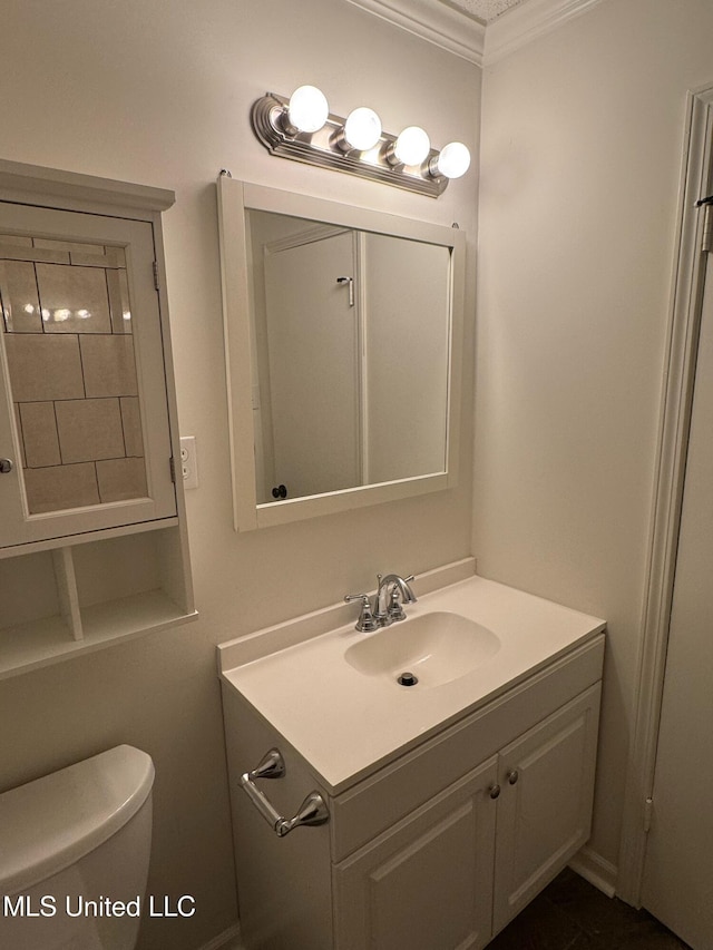 bathroom with ornamental molding, vanity, and toilet