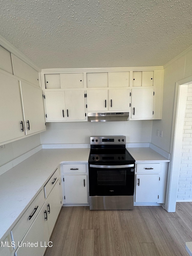 kitchen with under cabinet range hood, electric range, light wood-style flooring, and light countertops