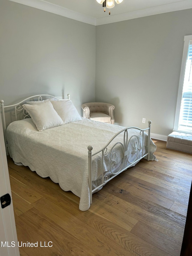 bedroom with multiple windows, crown molding, and hardwood / wood-style floors