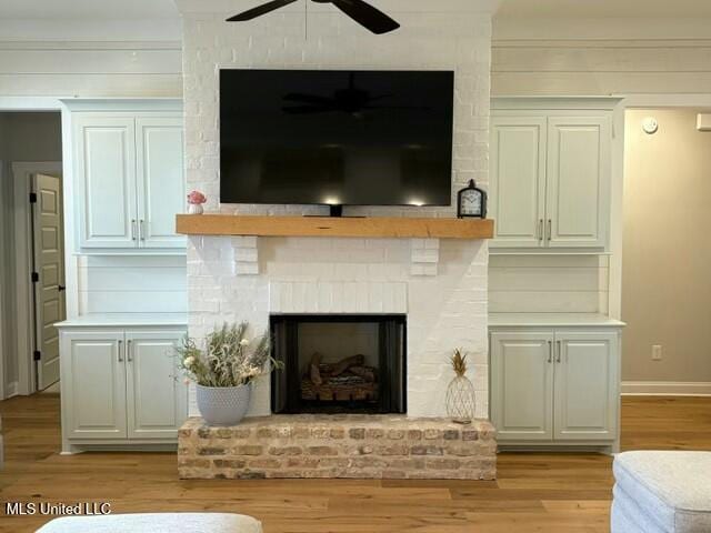 interior details featuring a brick fireplace, hardwood / wood-style floors, and ceiling fan