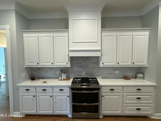 kitchen featuring white cabinetry, decorative backsplash, stainless steel range with gas cooktop, and range hood