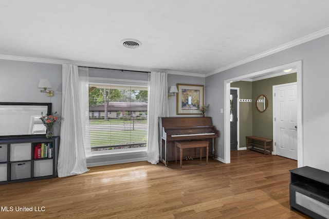 living area with baseboards, visible vents, ornamental molding, and wood finished floors