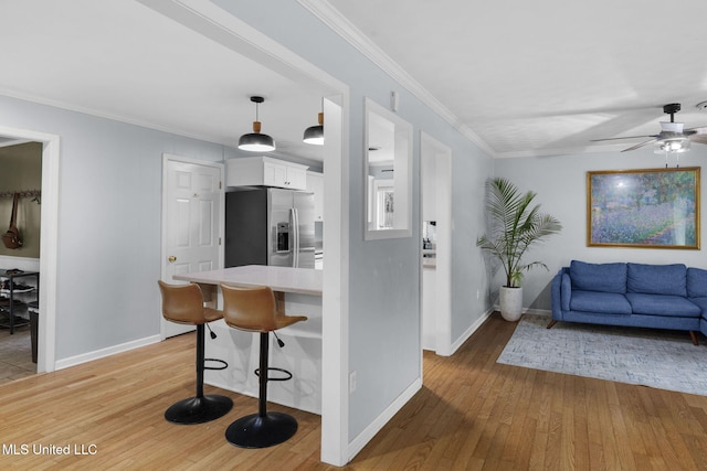 kitchen featuring ceiling fan, stainless steel fridge, light countertops, white cabinetry, and light wood-type flooring