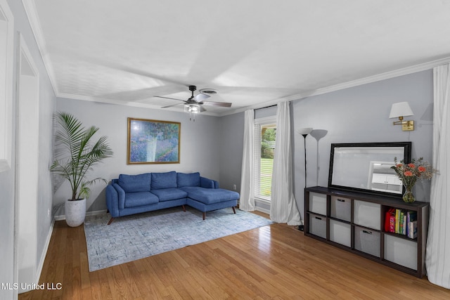 living room with crown molding, a ceiling fan, baseboards, and wood finished floors