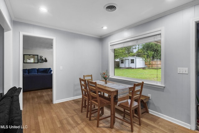 dining room featuring light wood-style floors, baseboards, ornamental molding, and visible vents