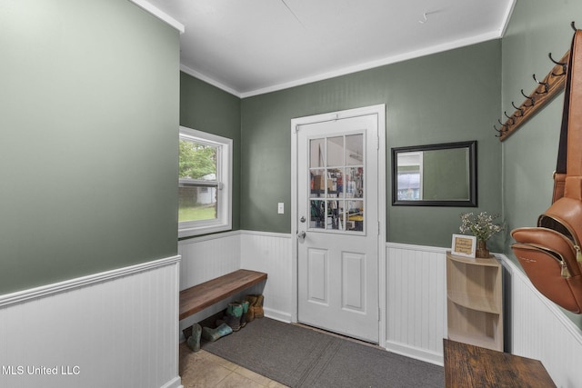 doorway to outside featuring tile patterned floors, ornamental molding, and wainscoting