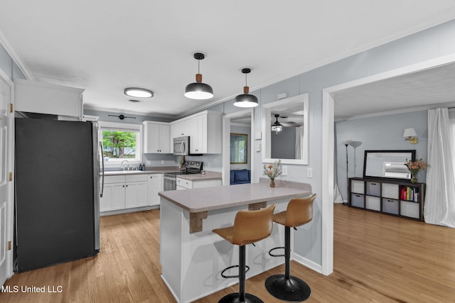 kitchen featuring a sink, stainless steel appliances, a ceiling fan, white cabinetry, and a peninsula