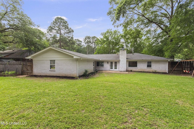 rear view of property with french doors, fence, a chimney, and a lawn