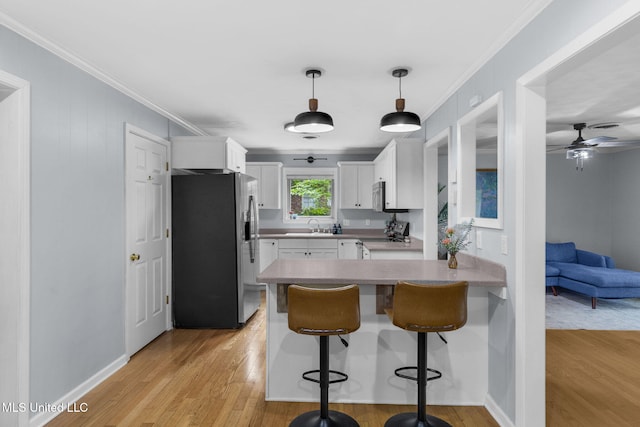 kitchen featuring light wood-type flooring, a sink, white cabinets, a peninsula, and stainless steel appliances