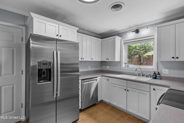 kitchen featuring a sink, appliances with stainless steel finishes, ornamental molding, and white cabinets