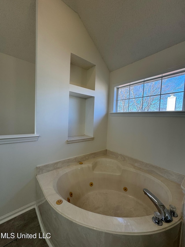 bathroom featuring tile patterned flooring, a textured ceiling, vaulted ceiling, and a bathtub