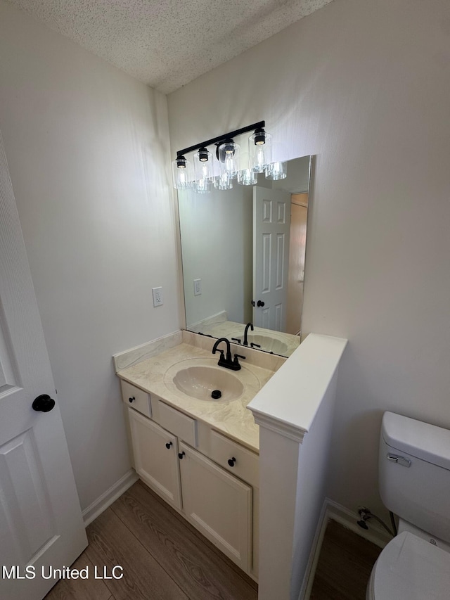 bathroom with hardwood / wood-style floors, vanity, a textured ceiling, and toilet