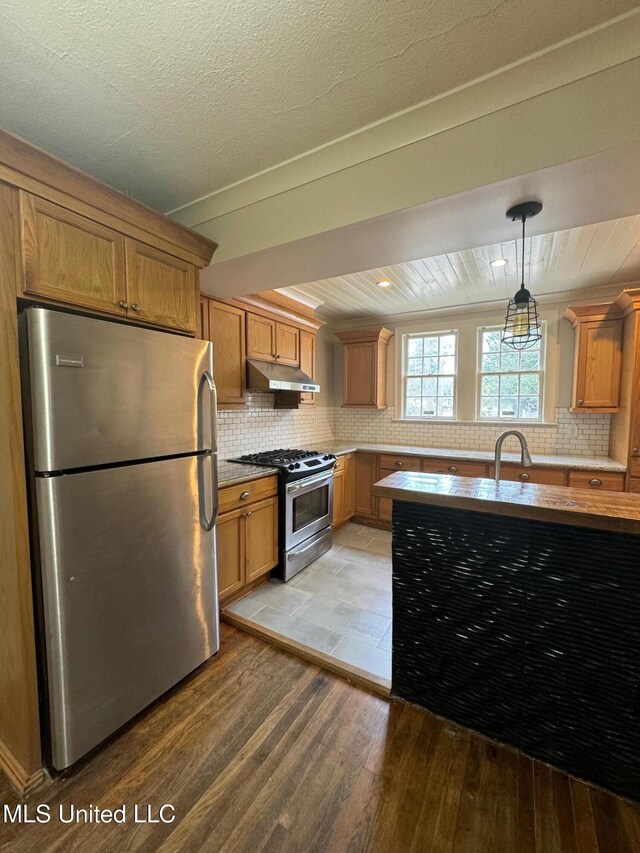 kitchen with stainless steel appliances, sink, tasteful backsplash, pendant lighting, and light wood-type flooring