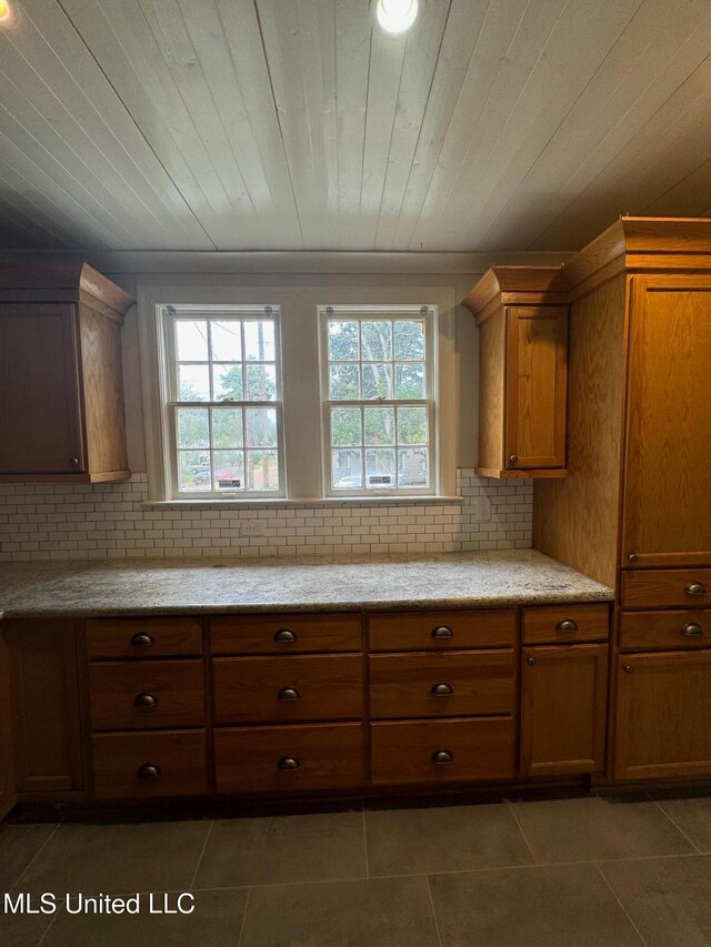 kitchen with dark tile patterned floors, decorative backsplash, and a healthy amount of sunlight