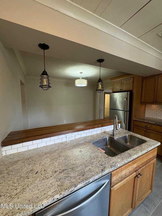 kitchen with sink, pendant lighting, appliances with stainless steel finishes, and tasteful backsplash