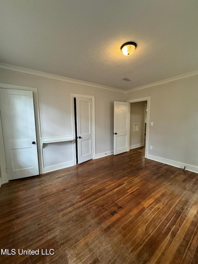 unfurnished bedroom with dark wood-type flooring, a textured ceiling, and crown molding