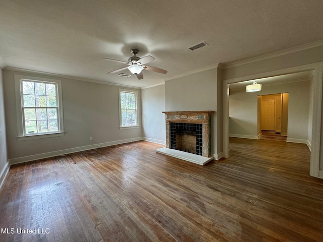 unfurnished living room featuring a tiled fireplace, ceiling fan, a healthy amount of sunlight, and dark hardwood / wood-style floors