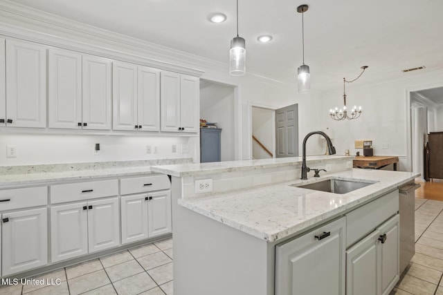 kitchen featuring white cabinets, hanging light fixtures, sink, and a kitchen island with sink