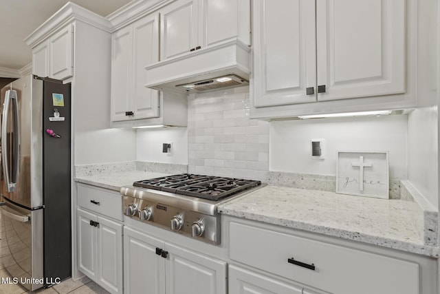 kitchen with light stone counters, stainless steel appliances, white cabinets, and premium range hood