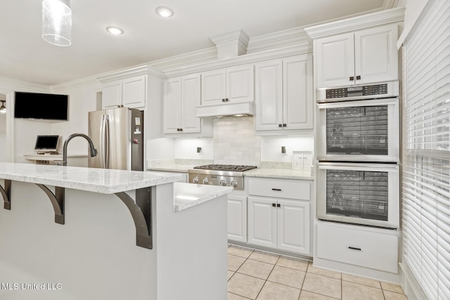 kitchen featuring stainless steel appliances, white cabinetry, a kitchen island with sink, and decorative light fixtures