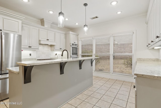 kitchen featuring a breakfast bar area, stainless steel refrigerator, ornamental molding, pendant lighting, and white cabinets