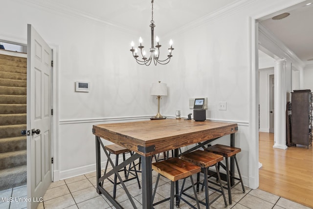 tiled dining room with ornate columns, ornamental molding, and a chandelier