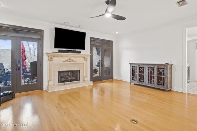 unfurnished living room with hardwood / wood-style flooring, a high end fireplace, ornamental molding, and french doors