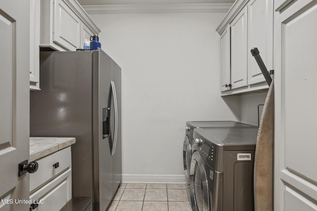 clothes washing area featuring cabinets, crown molding, separate washer and dryer, and light tile patterned floors