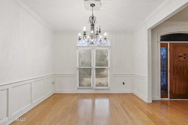 unfurnished dining area featuring an inviting chandelier, crown molding, and light hardwood / wood-style flooring