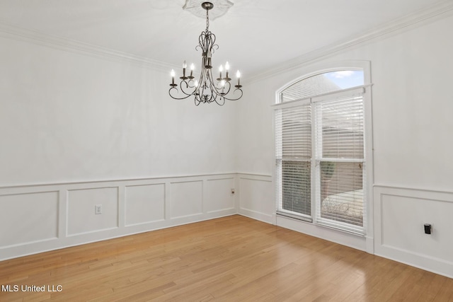 unfurnished room with ornamental molding, a notable chandelier, and light wood-type flooring