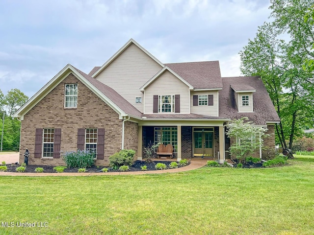 craftsman-style home with roof with shingles, a front lawn, brick siding, french doors, and covered porch