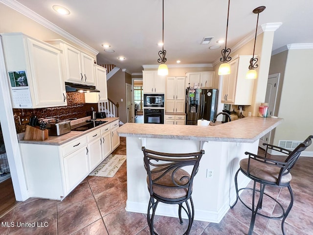 kitchen with a breakfast bar area, visible vents, tasteful backsplash, black appliances, and a peninsula