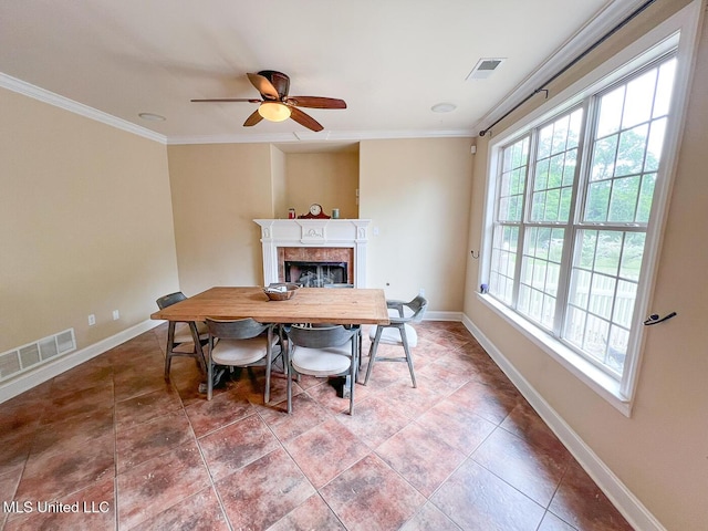 tiled dining space with ornamental molding, a fireplace, a ceiling fan, and visible vents