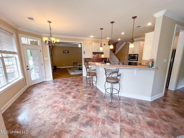 kitchen featuring crown molding, a breakfast bar area, built in microwave, and visible vents