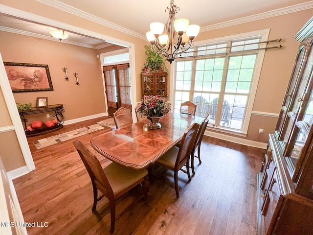 dining space with an inviting chandelier, baseboards, ornamental molding, and wood finished floors