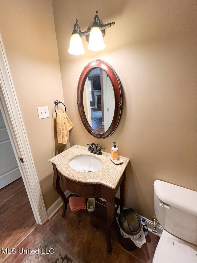 bathroom with toilet, baseboards, a sink, and wood finished floors