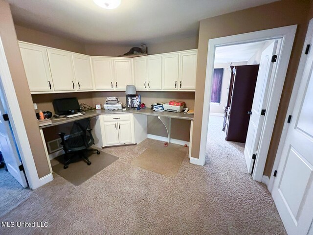 office area featuring built in study area, baseboards, and light colored carpet