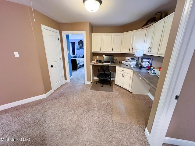 office area with baseboards, light carpet, and built in desk