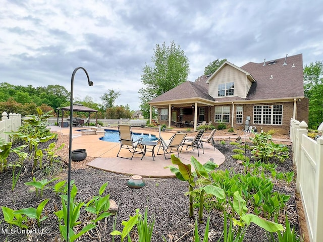 rear view of property with a gazebo, brick siding, a fenced in pool, a fenced backyard, and a patio area